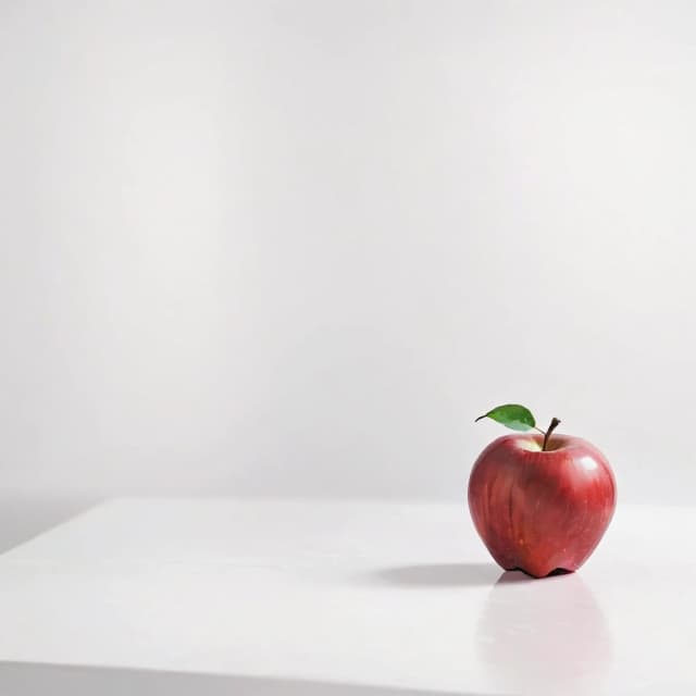 a red apple on a white table