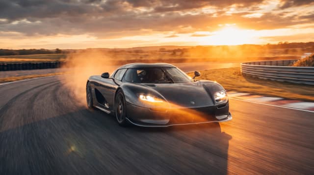Koenigsegg CC850, едет по гоночной трассе, эпичный ракурс, оранжевые лучи, горящие фары, эффект скорости, кинематографичная съёмка, шедевр