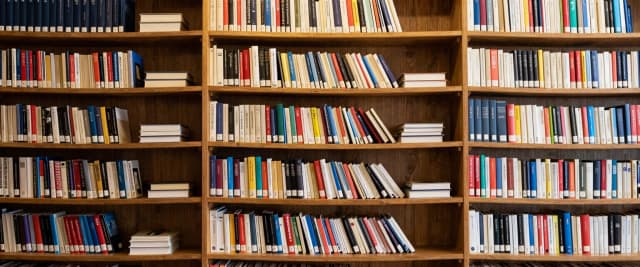Книжные шкафы, заполненные книгами. Книги стоят и лежат, нет пустых мест.