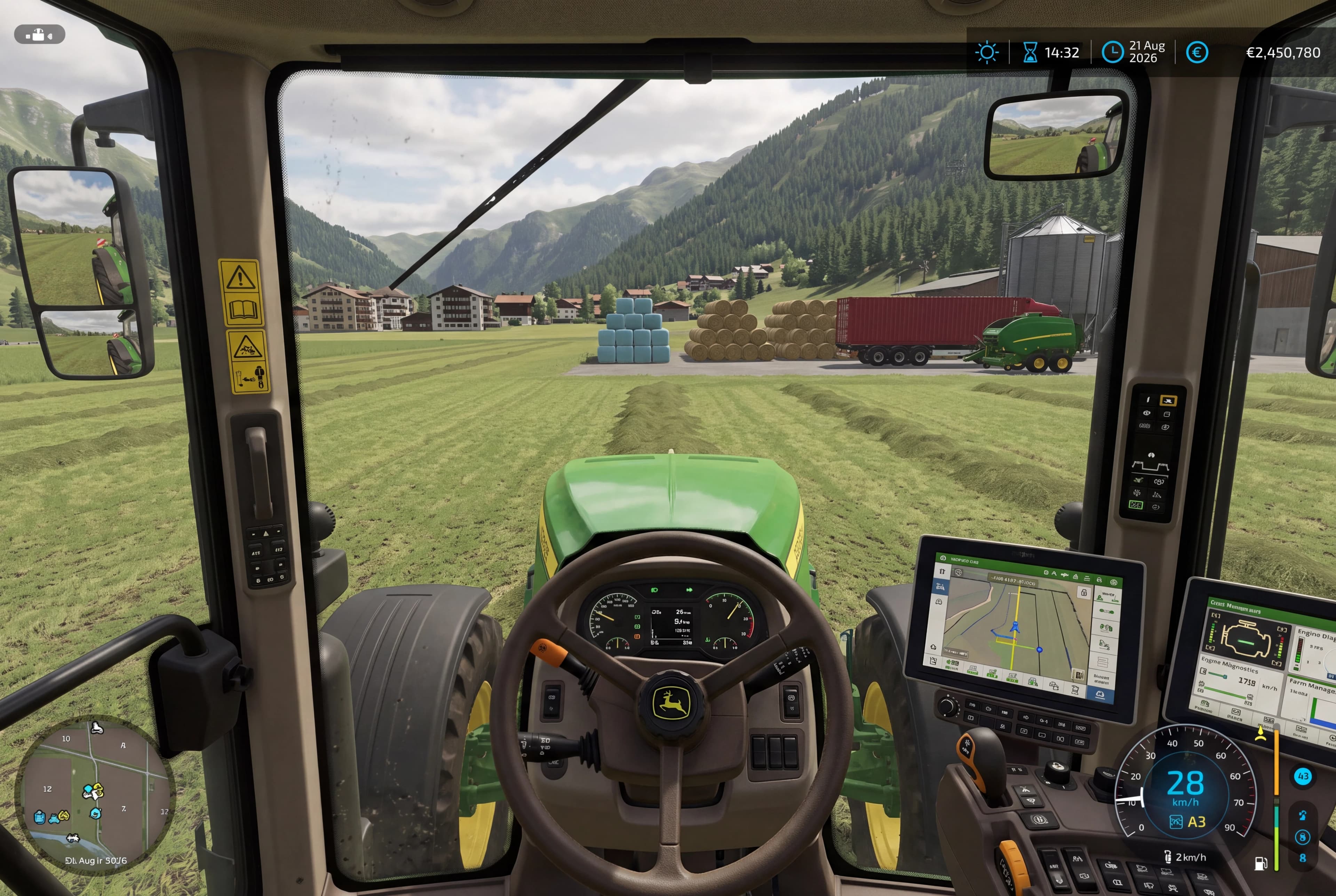 A detailed, first-person view from inside the cabin of a green John Deere agricultural tractor, looking out over a wide, sunlit green field in an alpine valley. The tractor hood is visible in the foreground. The cabin interior features a detailed dashboard with a multi-spoke steering wheel adorned with the John Deere logo, complex analog dials, and two large digital monitors displaying detailed GPS maps, farm data, and equipment status. A smaller mini-map is in the lower-left corner of the screen. The right-side control armrest with a joystick and side window are visible, alongside a detailed side mirror and vertical safety warning stickers on the left door frame. In the distance across the field is a collection of objects and vehicles: multiple large stacks of round hay bales (tan colored), several large stacks of wrapped blue bales, a long red articulated semi-trailer truck with a container, a green farm equipment implement, a distant village of multi-story buildings, and a large metal storage silo and other farm structures. The entire scene is framed by densely forested, steep mountains under a partly cloudy sky. The on-screen game HUD elements are visible, including the game time, date (21 August 2026), and currency balance in the top corners, and an intricate speed and status cluster in the bottom right, and mini-map in bottom left. The window has minor smudges and reflections. The atmosphere is clear and pastoral, under natural daylight.